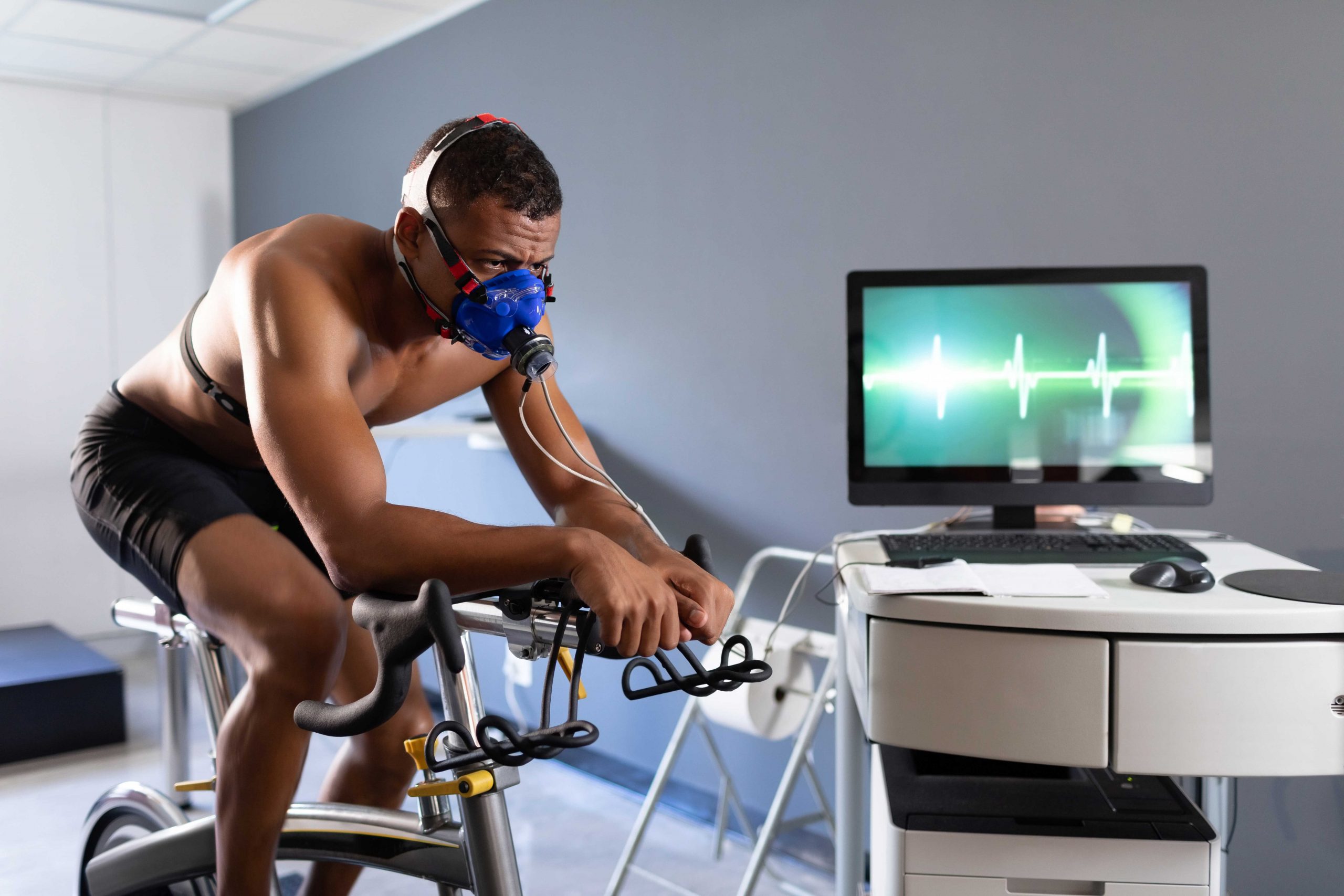 Man uses a stationary bike while being monitor by machines.