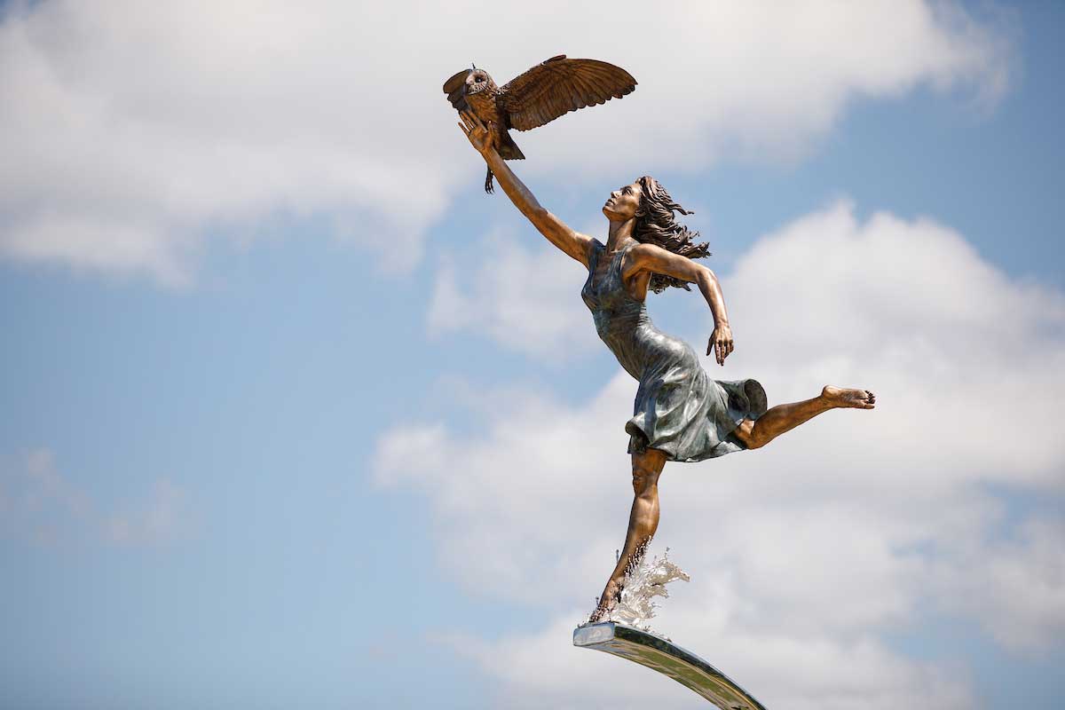 Bronze bicentennial statue of Minerva, the Roman goddess of wisdom, holding an owl shines in the sunlight at Manderson Landing in Tuscaloosa.