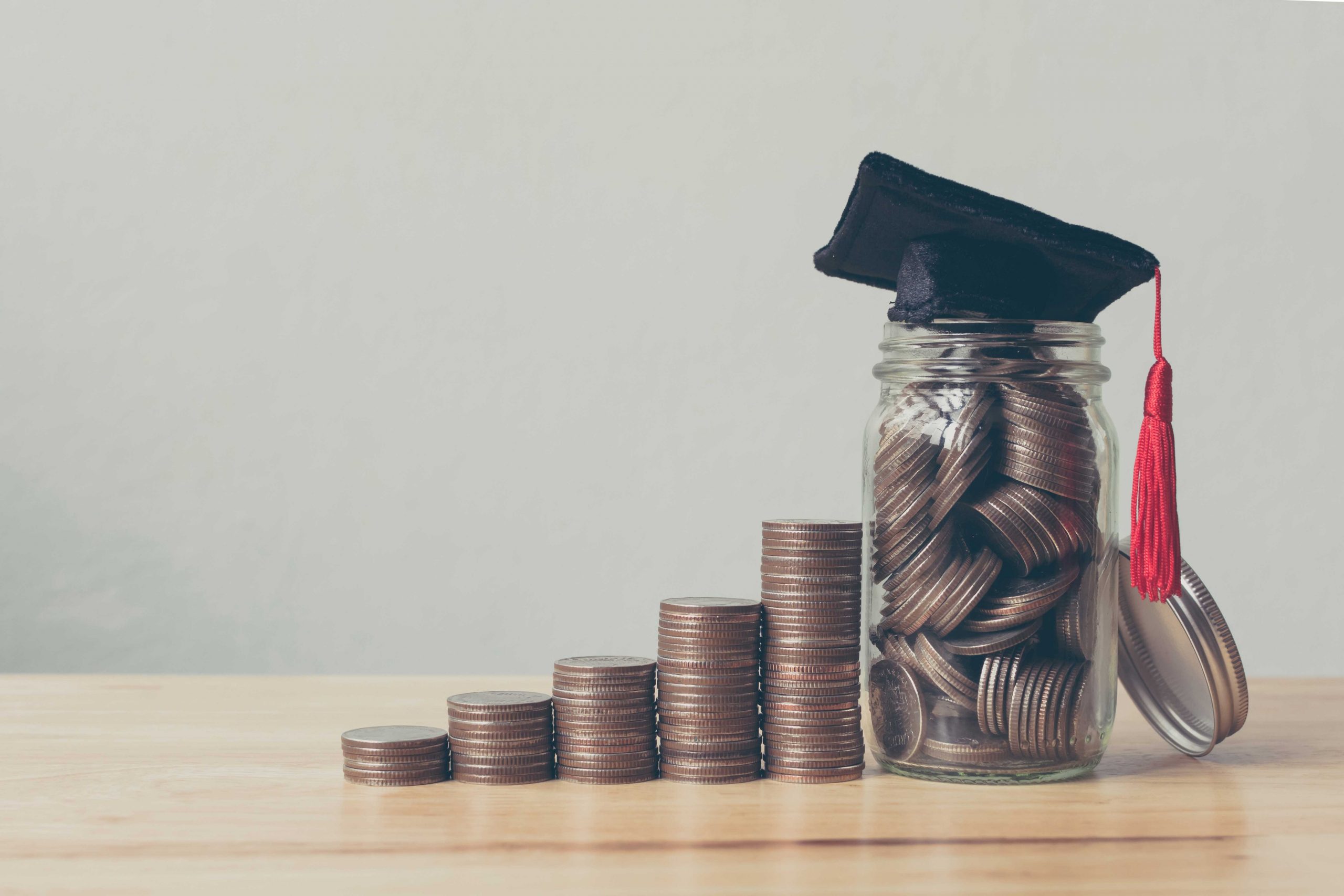 Change sits near a jar also filled with change. A graduation cap sits on top of the jar.