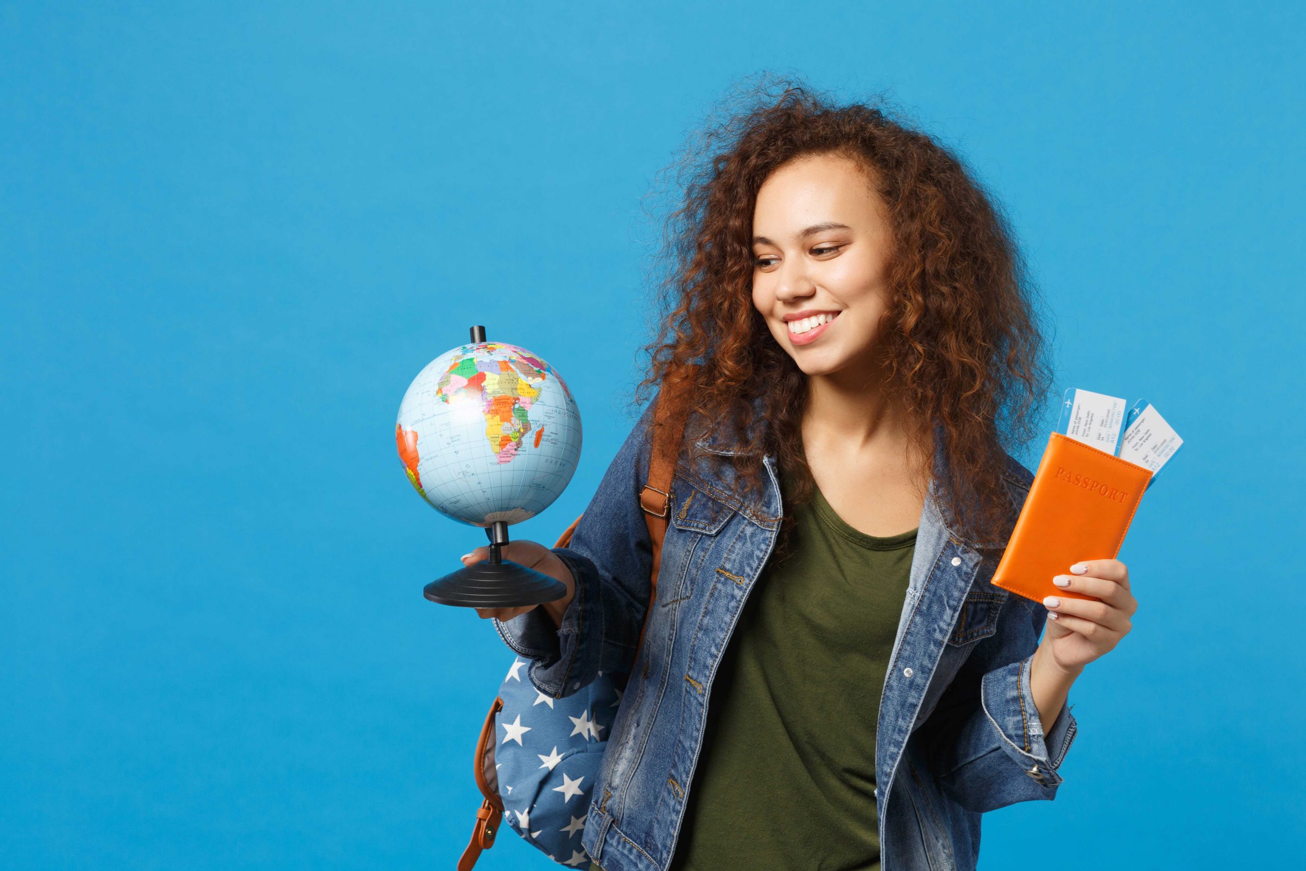 A student holds a small globe and her passport.