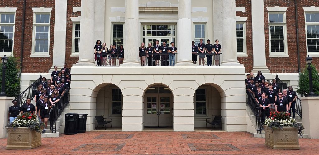2025 AP CSP Camp attendees pose for a photo on the exterior steps of the Honors College.