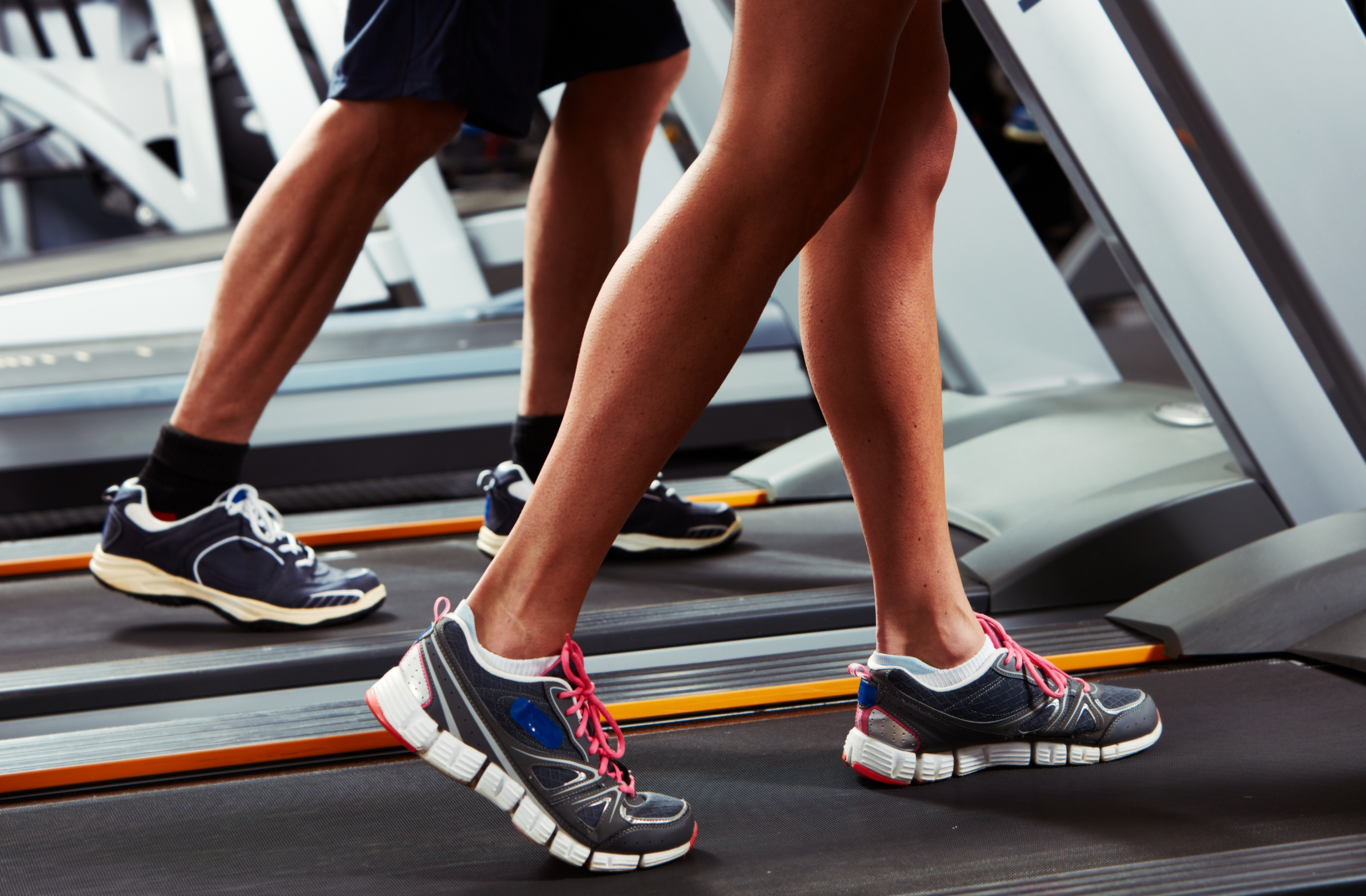 Two adults run on treadmills.