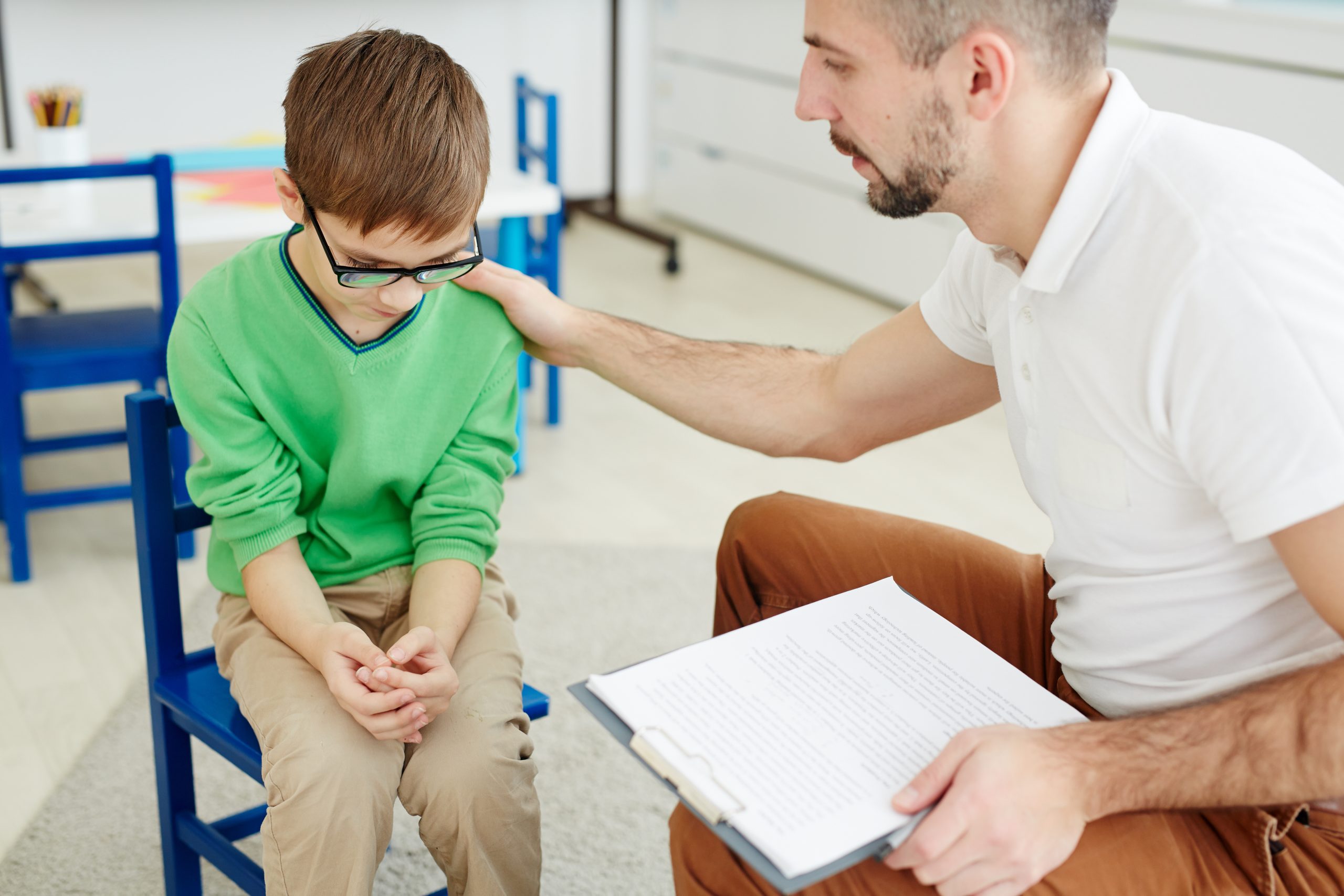 A school counselor tries to console a sad child.