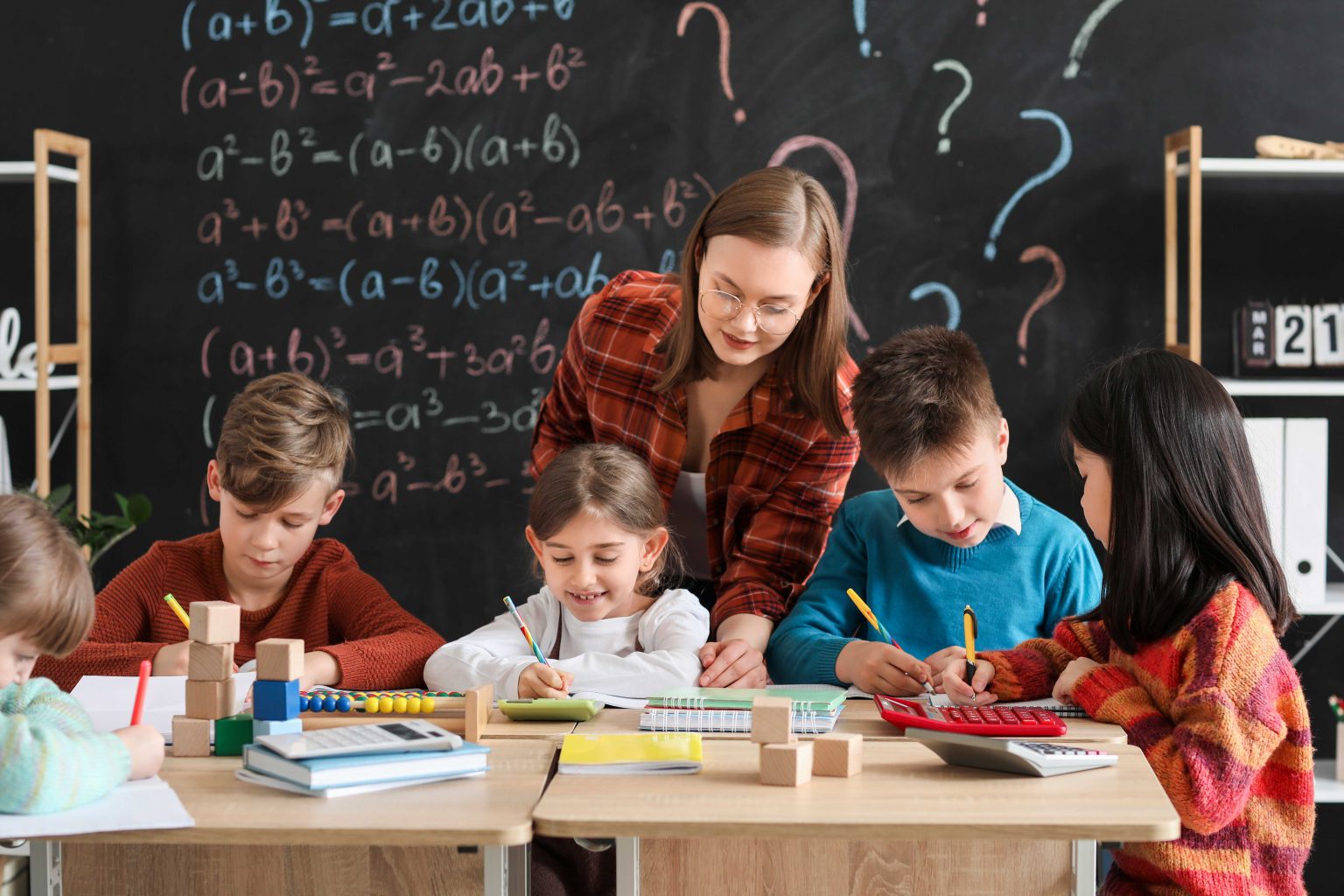 An elementary school math teacher works with students during class.